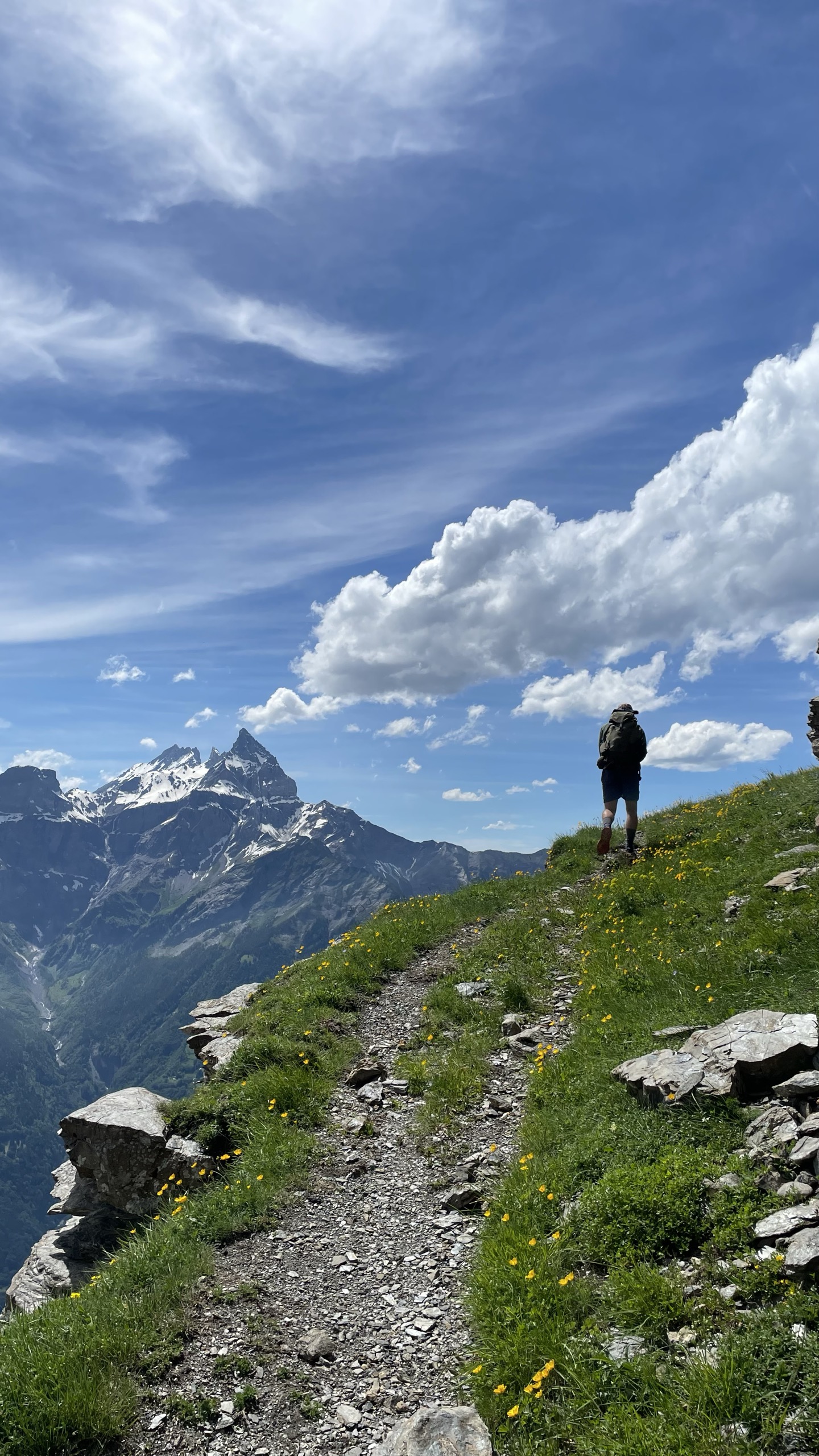 Randonneur sur sentier alpin face aux sommets enneigés